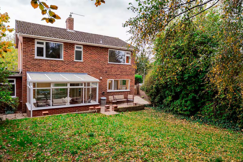 Brick suburban house with modern extension, garden and autumn foliage