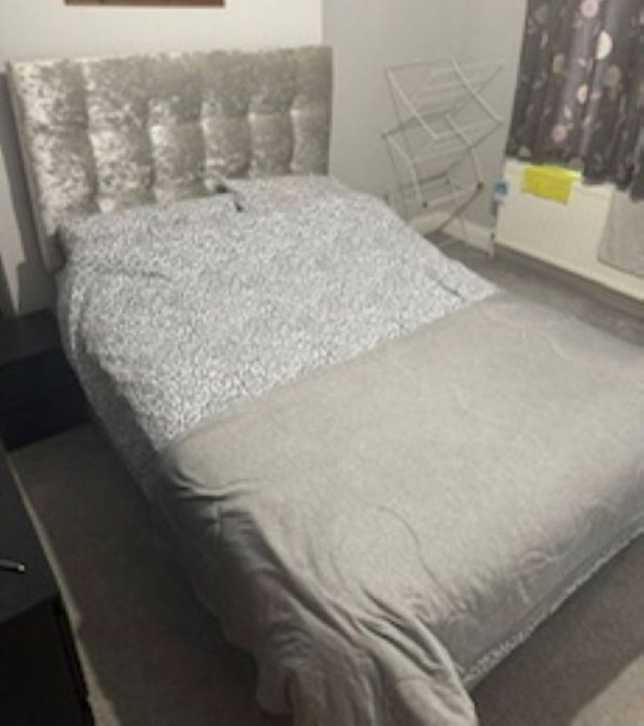 Bedroom with double bed, patterned headboard, grey bedding and curtains