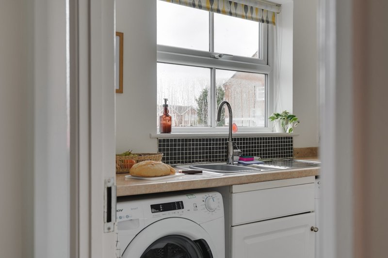 Compact kitchen with window, sink, washing machine and wooden countertop with décor