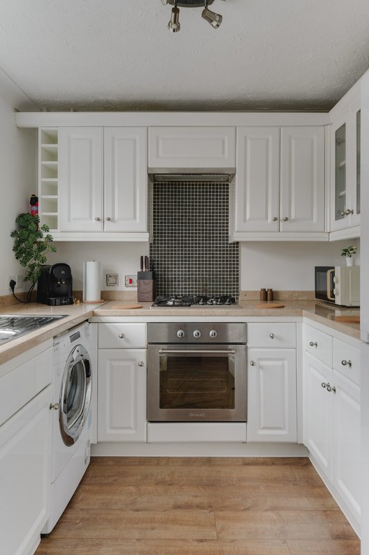 Modern white kitchen with built-in oven, hob, washing machine and wooden countertops