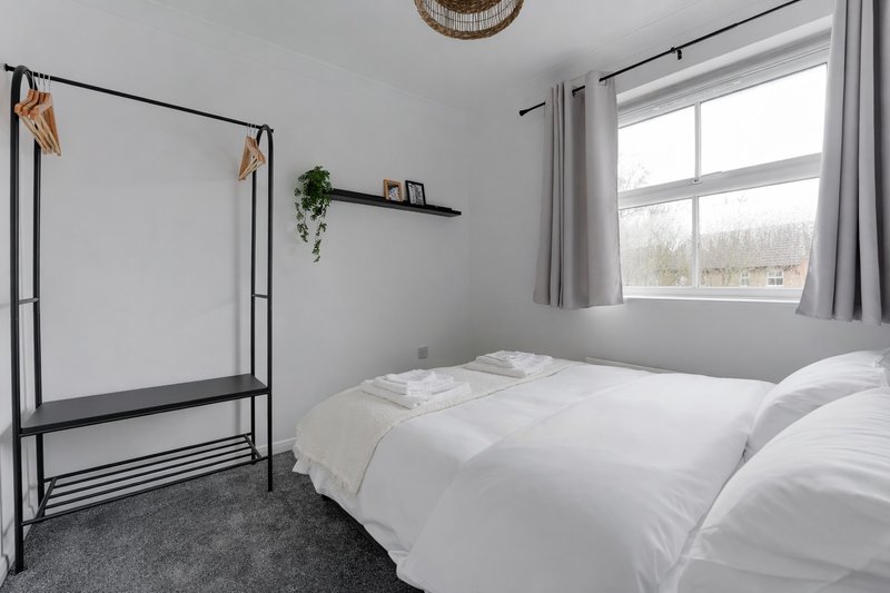 Bright bedroom with double bed, metal four-poster frame, window and potted plant on shelf