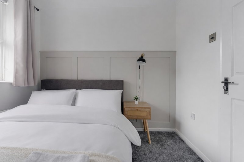 Modern bedroom with double bed, dark headboard, wooden nightstand and pendant lamp