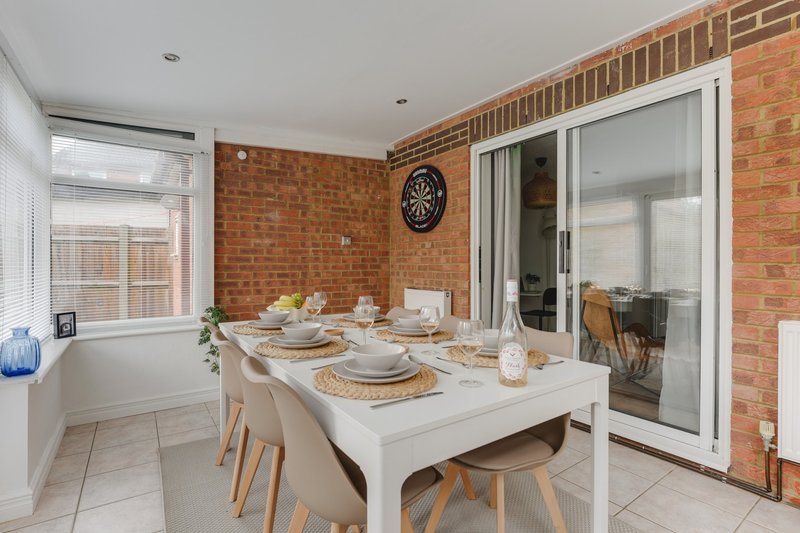Modern dining room with white table, wooden chairs, brick wall and patio doors
