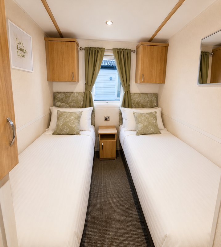 Twin bedroom with two single beds, green cushions, wooden storage and window with curtains