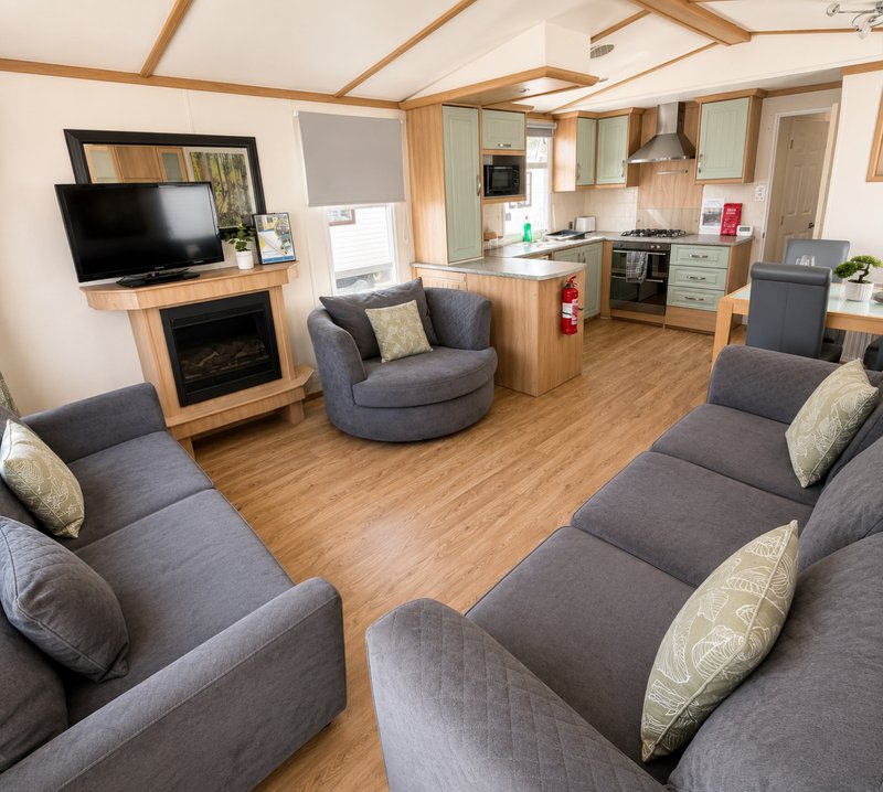 Open-plan living space with sofas, TV, fireplace, kitchen area and wooden beams