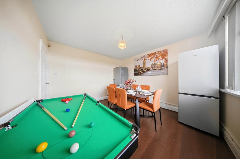 Open-plan recreation room with pool table, dining area, refrigerator and wall art