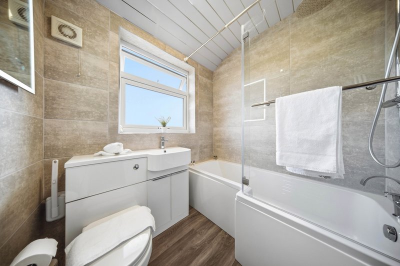 Modern bathroom with white suite, bath, sink, toilet, towel rail and window