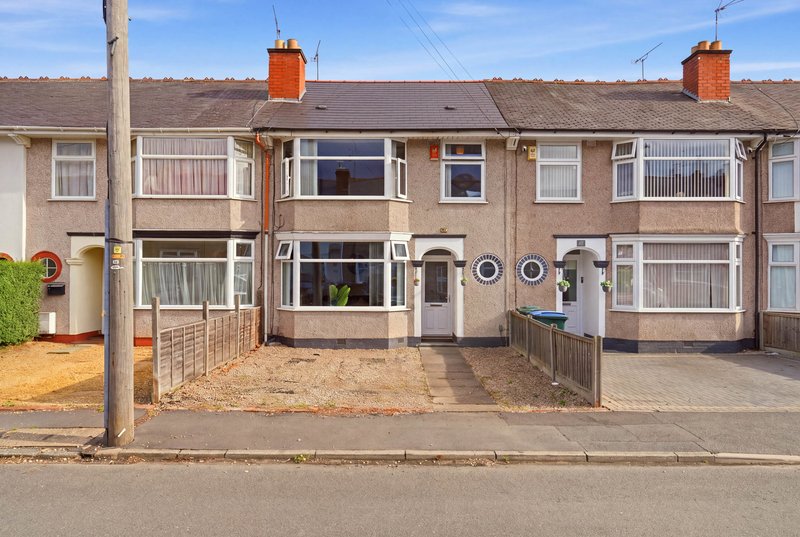 Terraced brick houses with front gardens, driveways and parked vehicles on residential street