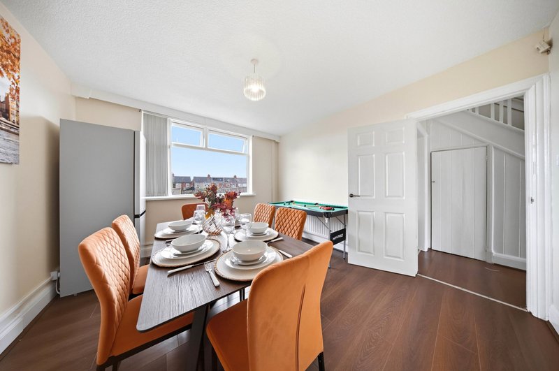 Dining room with wooden table, orange chairs, place settings and city view