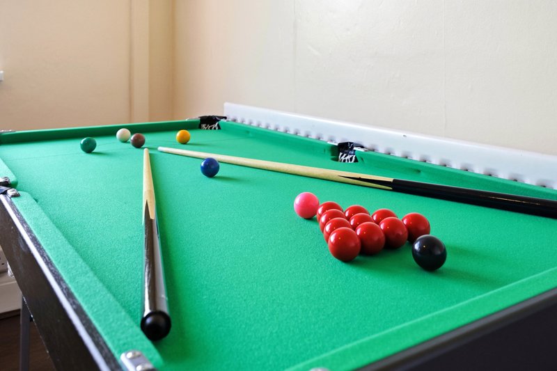 Pool table with balls and cues set up for snooker game