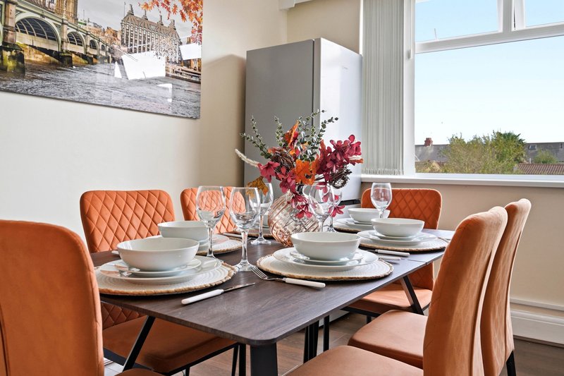Modern dining room with black table, orange upholstered chairs, place settings and floral centerpiece
