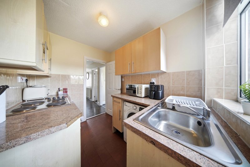 Kitchen with cream and wood cabinets, granite countertops, stainless steel sink and appliances