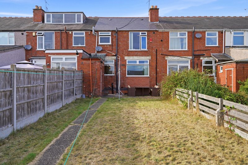 Red brick terraced house with garden, wooden fencing, and adjacent properties visible