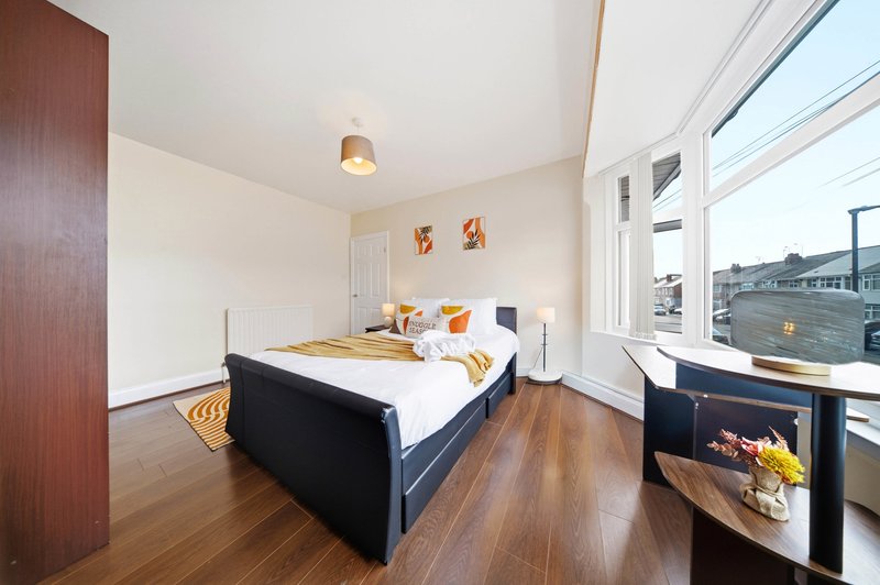 Bright bedroom with double bed, wooden flooring, large windows and city views
