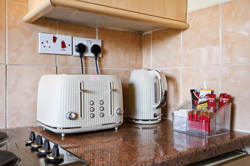 Kitchen countertop with white toaster, kettle, organizer, and condiment holder