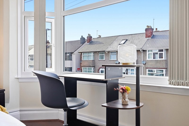 Modern home office with black desk, chair and shelving unit overlooking residential street