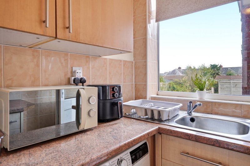 Kitchen with wooden cabinets, countertop appliances, sink and window overlooking garden