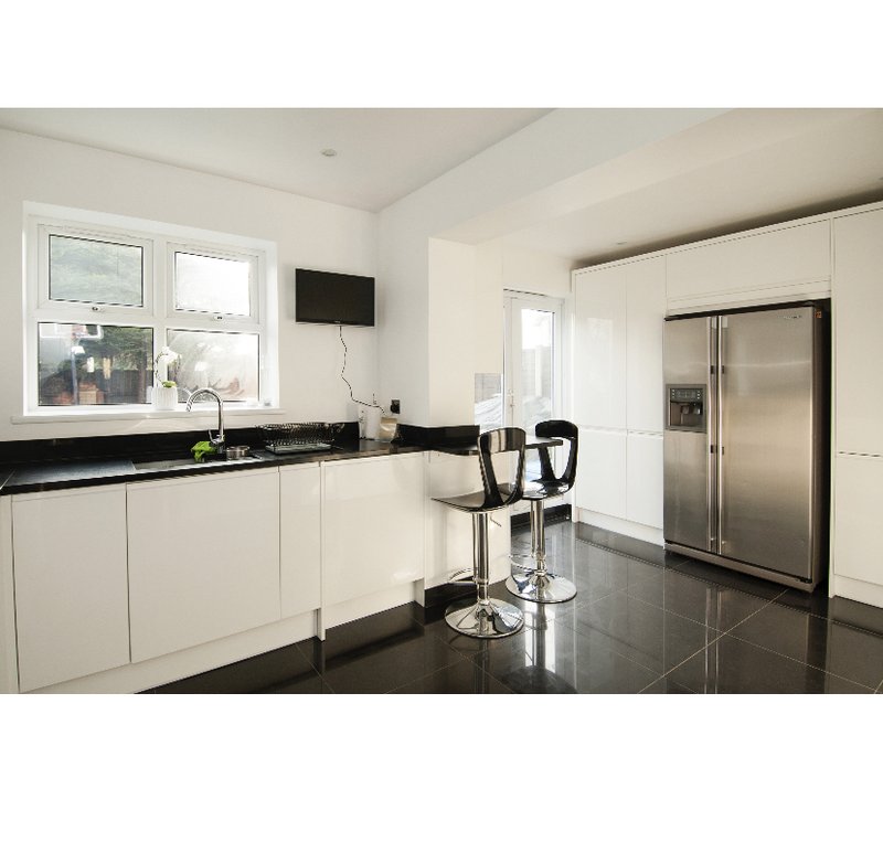 Modern kitchen with white cabinetry, black countertops, stainless steel appliances and bar seating