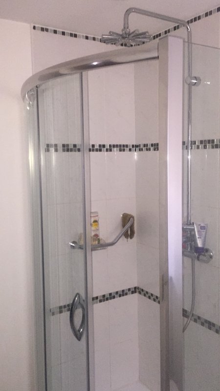 Modern shower enclosure with curved glass doors, chrome fixtures and tiled walls