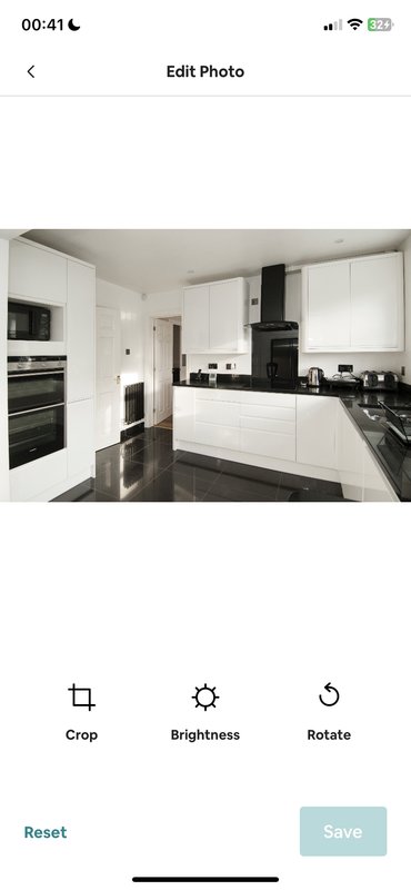 Modern kitchen with white cabinetry, black countertops, integrated appliances and dark flooring