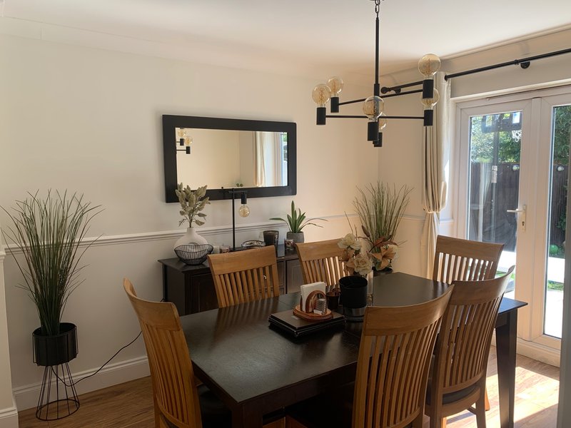Dining room with dark table, wooden chairs, mirror, pendant lighting and glass doors to garden