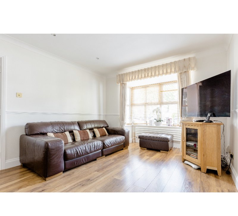 Bright living room with brown leather sofa, wooden TV unit, fireplace and large window with curtains