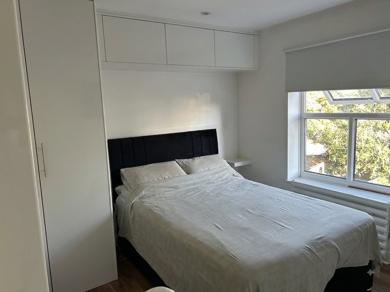 Modern bedroom with double bed, black headboard, built-in wardrobes and large window