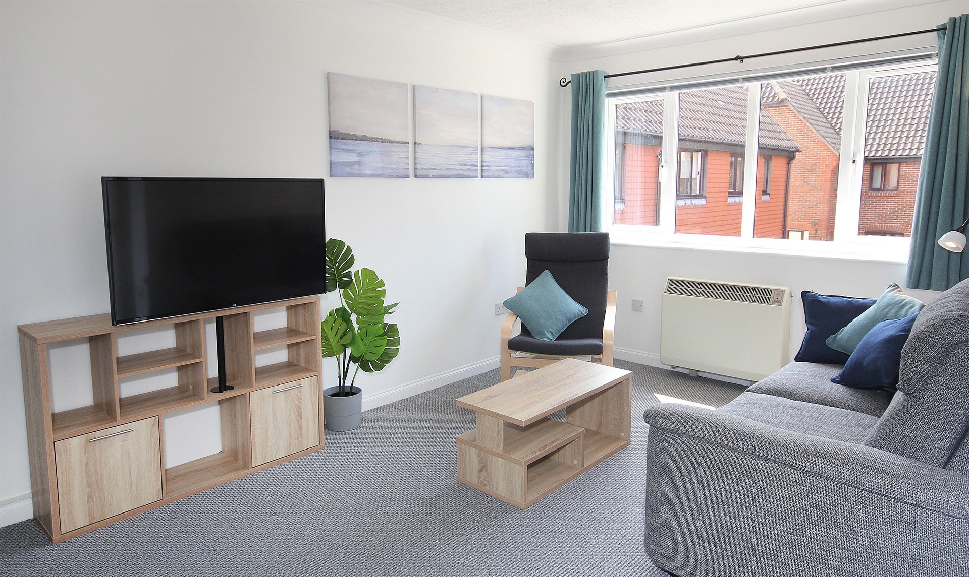Modern living room with gray sofa, wooden TV unit, coffee table and window view