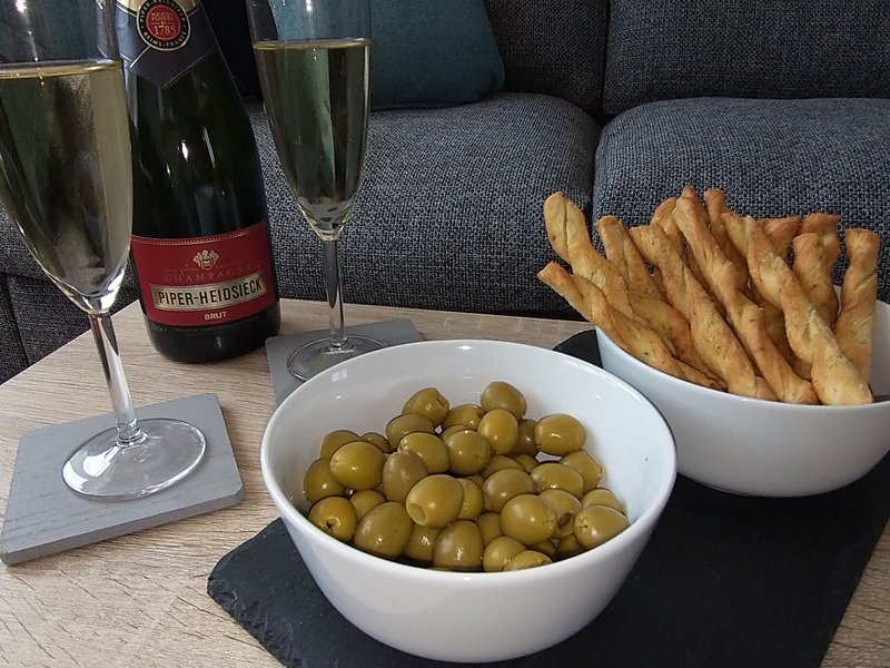 Styled table with champagne bottle, glasses, olives in bowl, and breadsticks