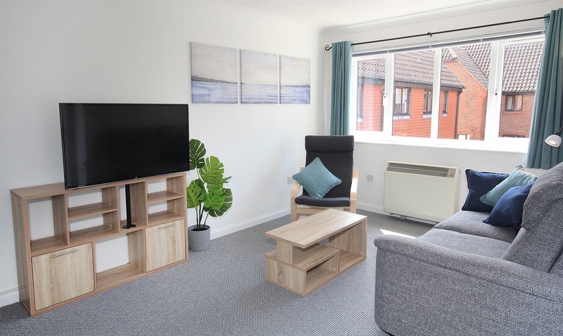 Modern living room with gray sofa, TV, wooden storage unit and coffee table