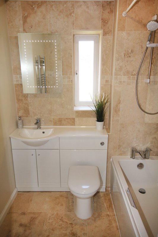 Modern bathroom with vanity unit, mirror, toilet, bathtub and tiled walls