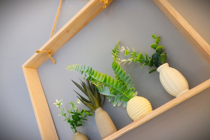 Wooden shelf with potted plants and ferns against gray wall