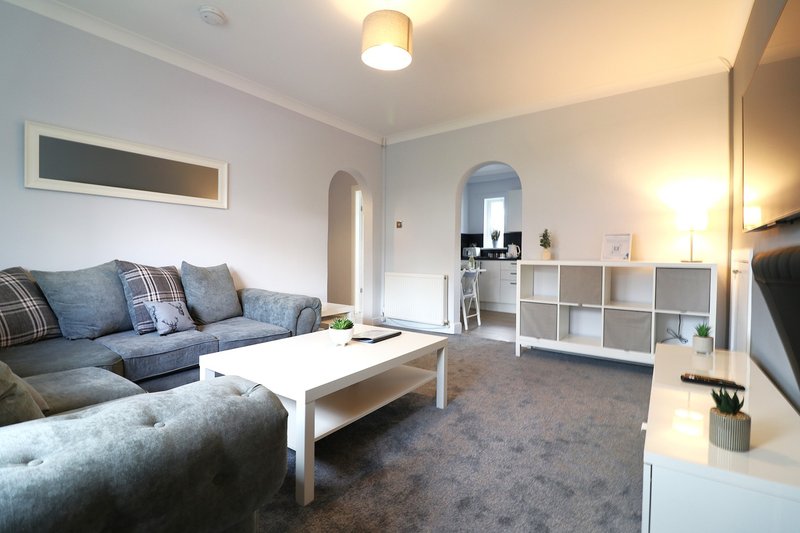 Spacious living room with grey sofa, white coffee table, storage shelving and modern lighting