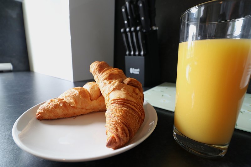 Kitchen counter with plate of croissants, orange juice glass, and knife block