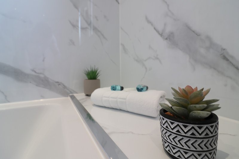 Modern bathroom with marble countertop, white towel, potted succulents and decorative accessories