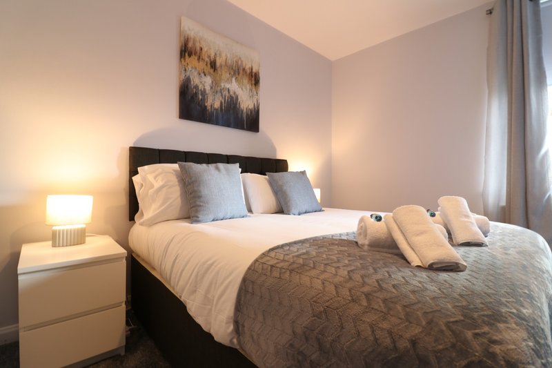 Modern bedroom with black bed frame, white bedding, decorative pillows and wall art