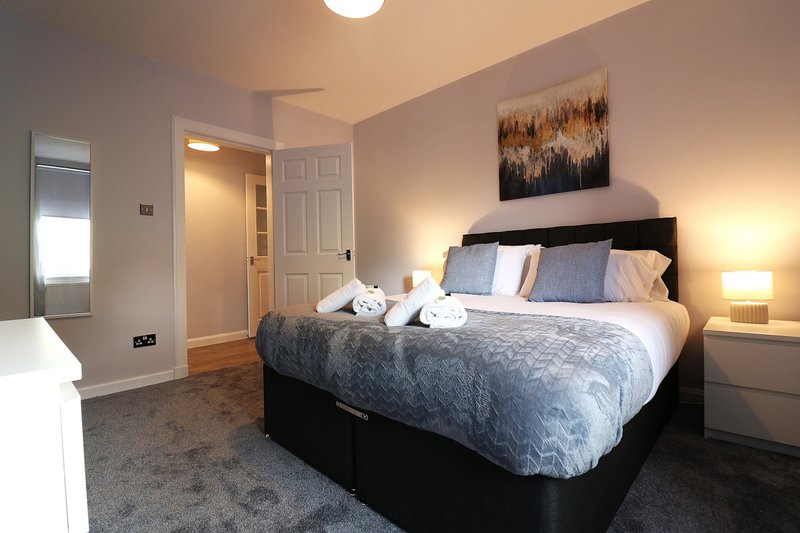 Modern bedroom with double bed, blue bedding, two bedside lamps, and abstract wall art