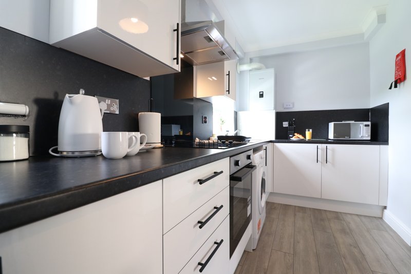 Modern kitchen with white cabinetry, black countertop, stainless steel appliances and pendant lighting