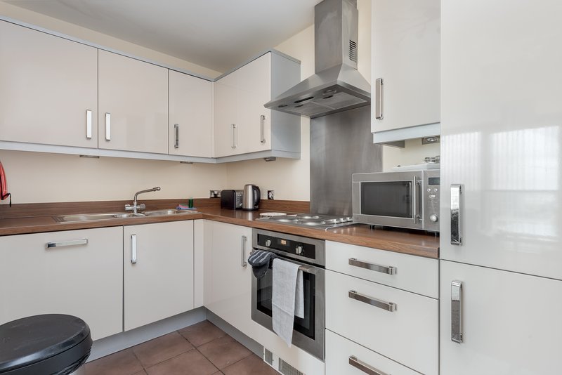 Modern kitchen with white cabinetry, brown worktops, stainless steel appliances and extractor hood