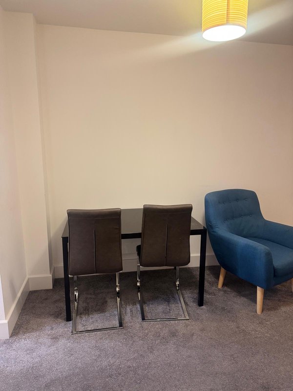 Seating area with two brown chairs, blue armchair, and yellow ceiling light