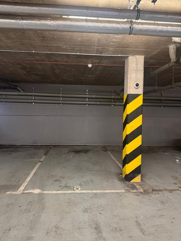 Underground parking space with yellow and black striped concrete pillar