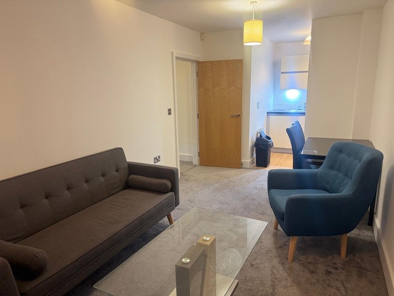 Modern living room with dark sofa, blue armchair, glass coffee table and pendant light