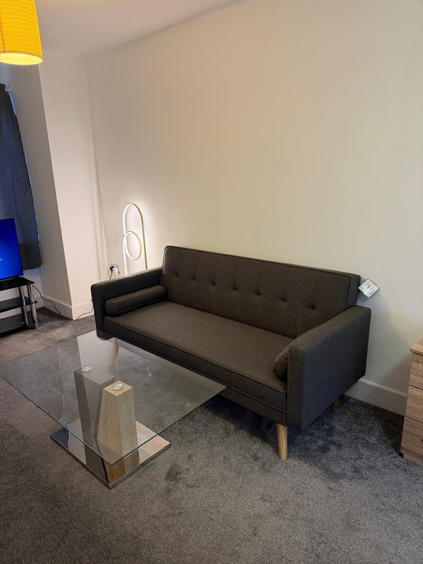 Modern living room with dark gray sofa, glass coffee table, and pendant light