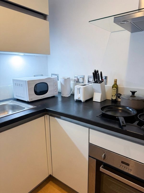Modern kitchen with white cabinetry, black countertop, microwave, and cooking appliances