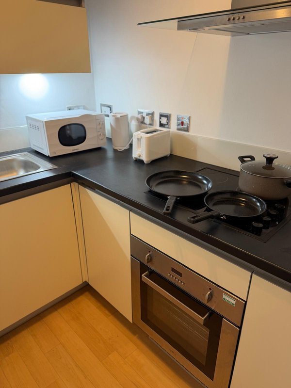 Modern kitchen with yellow cabinets, black countertop, integrated oven and hob, microwave and appliances