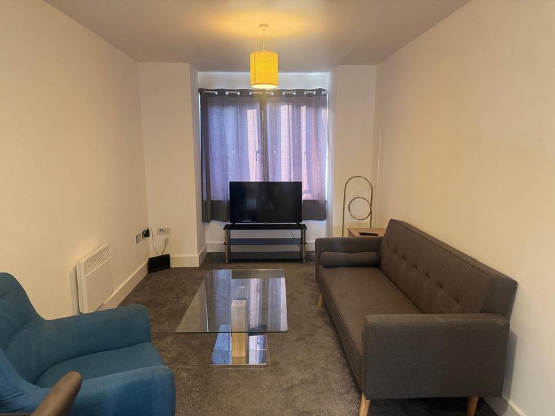 Living room with two sofas, TV on stand, window with striped curtains, yellow pendant light