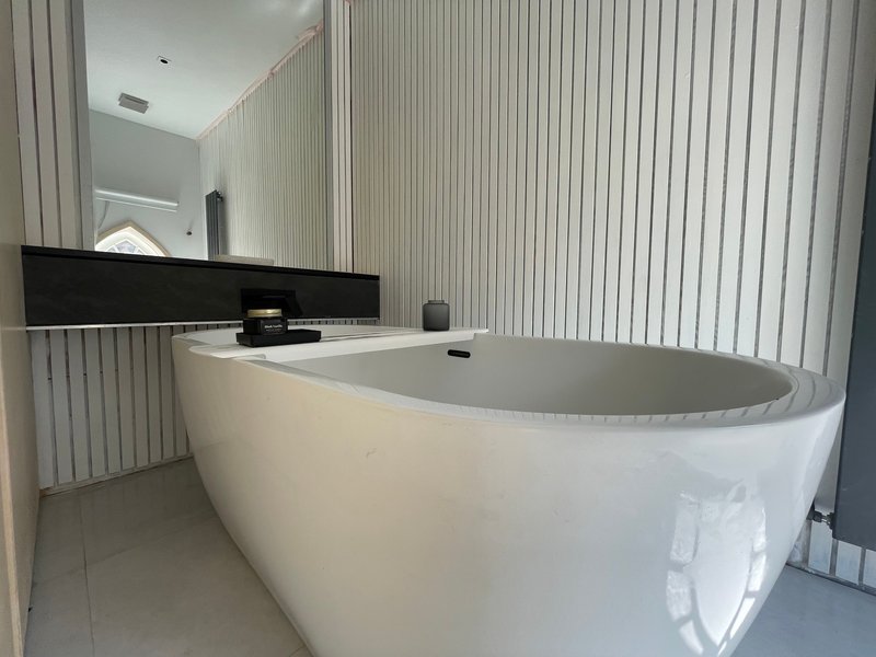 Modern bathroom with freestanding white bathtub, black vanity, and vertical blinds