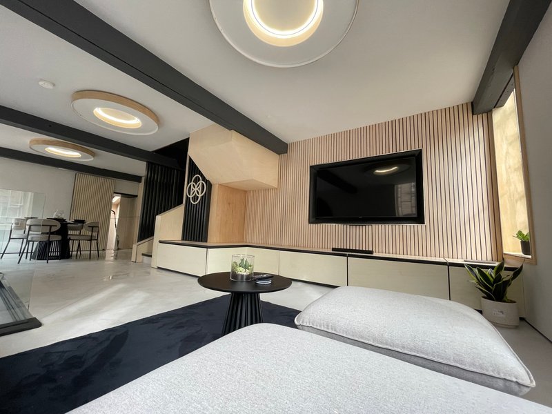 Modern bedroom with twin beds, wall-mounted TV, recessed lighting and minimalist furnishings