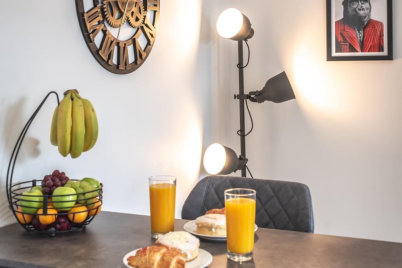 Dining table with fresh fruit bowl, breakfast items, and decorative lighting and wall art
