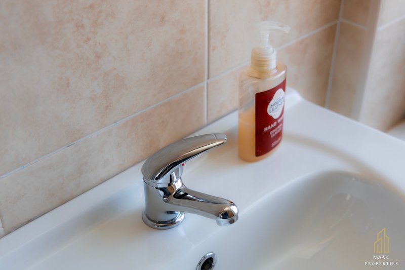 Bathroom sink with chrome faucet, soap dispenser, and toiletries on counter
